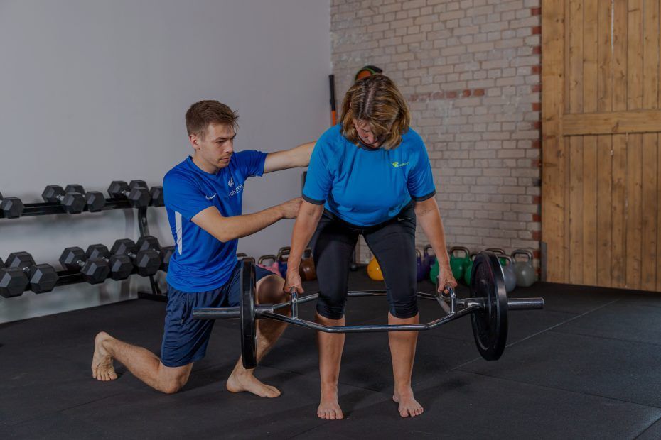 Eine Person hilft einer anderen Person, eine Hantel anzuheben, während sie sich auf das Training konzentrieren.
