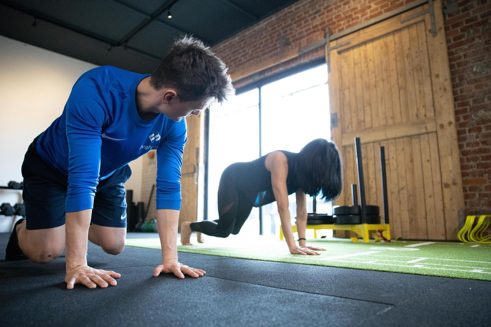 Ein Mann und eine Frau machen Liegestütze in einem Fitnessstudio.