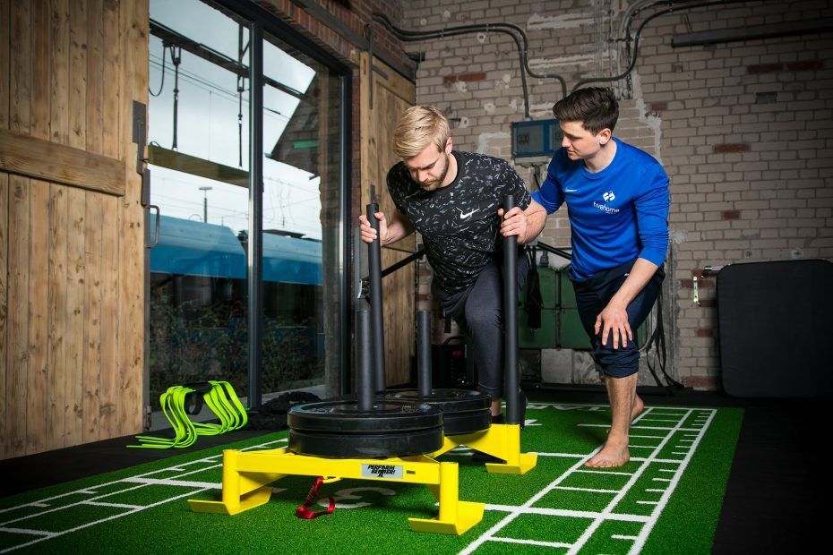 Zwei Personen trainieren gemeinsam an einem Fitnessgerät im Fitnessstudio.