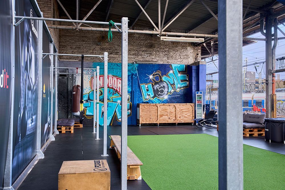 Outdoor-Räumlichkeiten mit Sitzgelegenheiten und verschiedenen Trainingsstationen von FiveHomeFitness