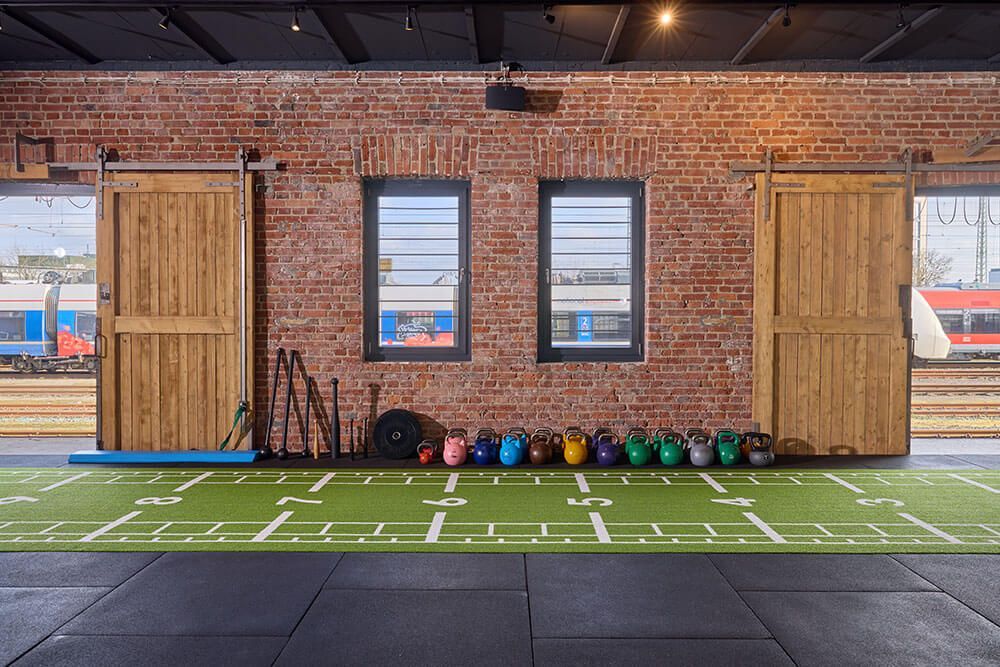 Ein Fitnessraum mit einem grünen Kunstrasenfeld, ausgestattet für verschiedene Sport- und Trainingsaktivitäten.