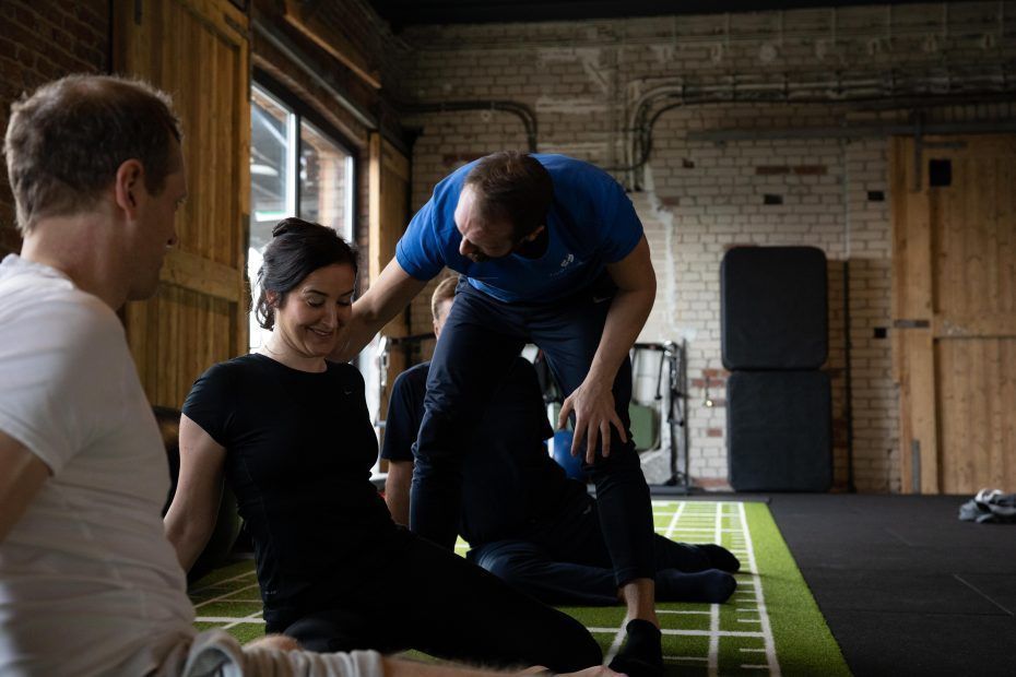 Mehrere Personen sitzen auf dem Boden und machen Dehnungsübungen.